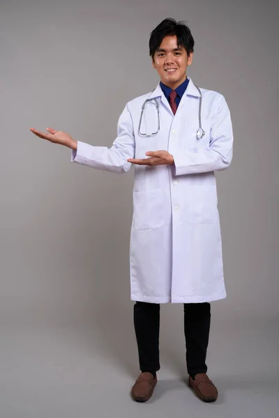 Pleine longueur portrait de heureux asiatique homme médecin montrant copie espace — Photo