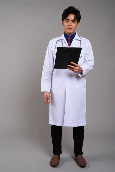 Retrato de cuerpo entero del joven asiático doctor sosteniendo portapapeles —  Fotos de Stock