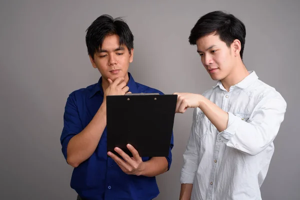 Két fiatal csinos ázsiai férfi olvasó csipeszes írótábla — Stock Fotó