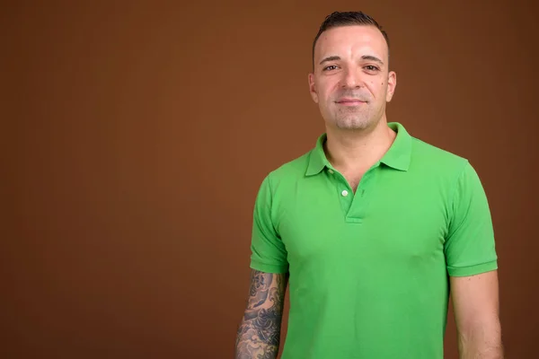 Uomo che indossa camicia verde sullo sfondo marrone — Foto Stock