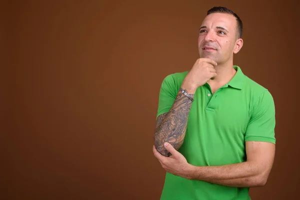 Hombre vistiendo camisa verde sobre fondo marrón — Foto de Stock