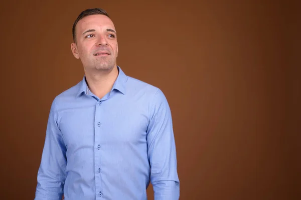 Businessman wearing blue shirt against brown background — Stock Photo, Image