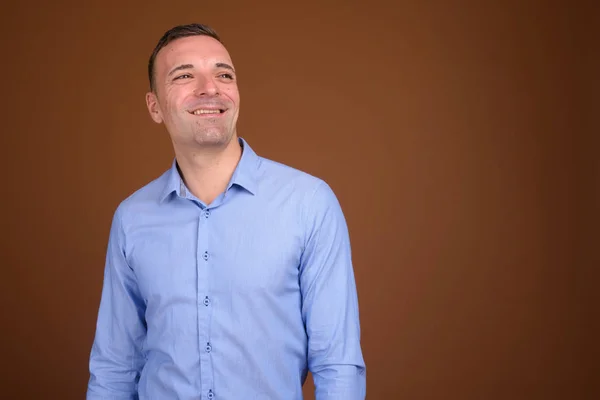 Businessman wearing blue shirt against brown background — Stock Photo, Image