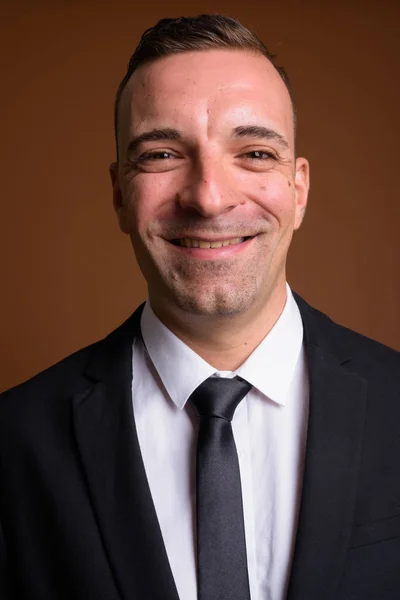 Portrait of businessman wearing suit against brown background — Stock Photo, Image