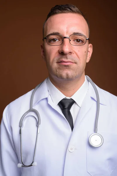 Férfi orvos visel szemüveget barna háttér — Stock Fotó