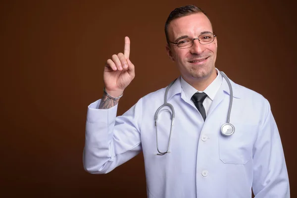 茶色の背景に対して眼鏡を身に着けている男医師 — ストック写真