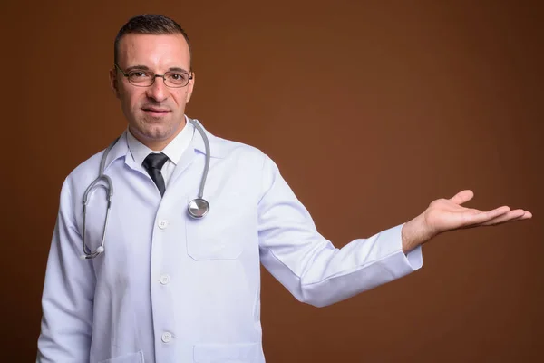 Homme médecin portant des lunettes sur fond brun — Photo