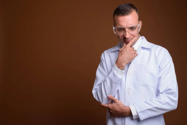 Uomo medico indossa occhiali protettivi contro sfondo marrone — Foto Stock