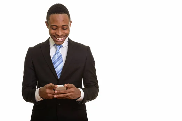 Młody, szczęśliwy afrykański biznesmen uśmiechnięty i korzystający z telefonu komórkowego — Zdjęcie stockowe