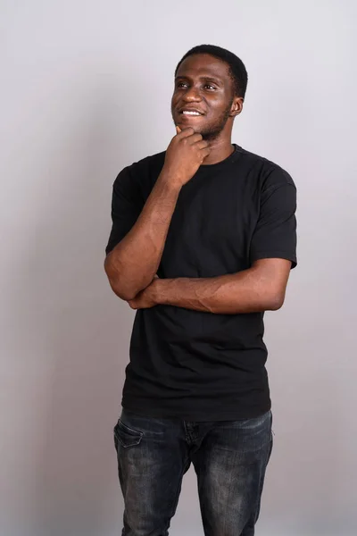 Young African man wearing black shirt against gray background — Stock Photo, Image