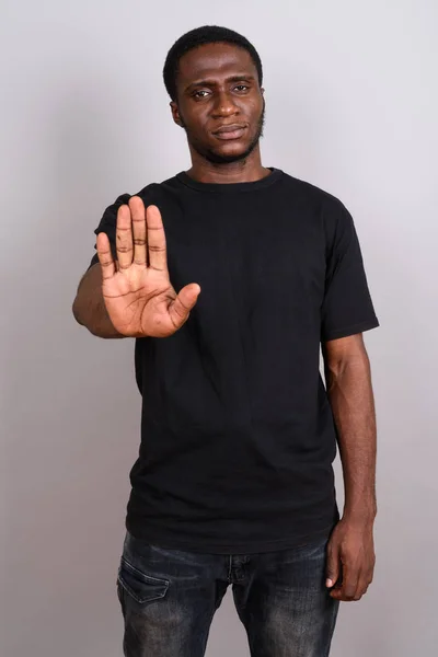 Joven hombre africano con camisa negra sobre fondo gris — Foto de Stock
