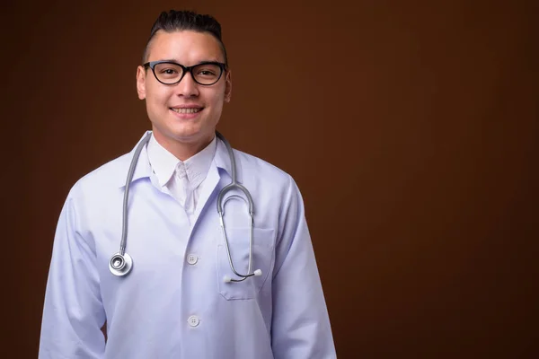 Young handsome multi-ethnic man doctor against brown background — Stock Photo, Image