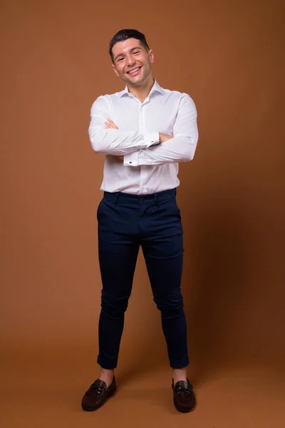 Portrét mladé pohledný podnikatel proti hnědým pozadím — Stock fotografie