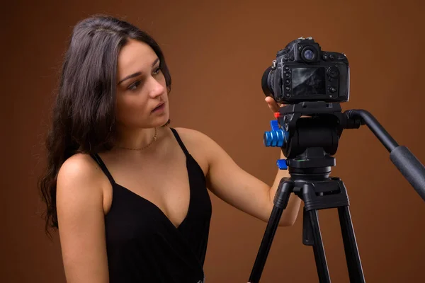 Studio shot van jonge mooie vrouw tegen bruine achtergrond — Stockfoto