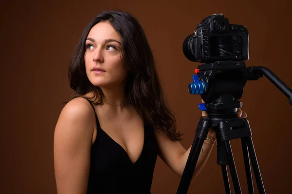 Studio shot van jonge mooie vrouw tegen bruine achtergrond — Stockfoto