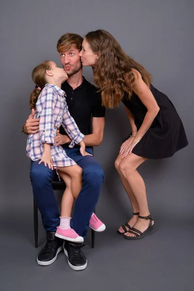 Jong gelukkig familie binding samen tegen grijs achtergrond — Stockfoto