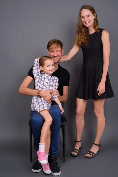 灰色の背景に対して一緒に若い幸せな家族の絆 — ストック写真