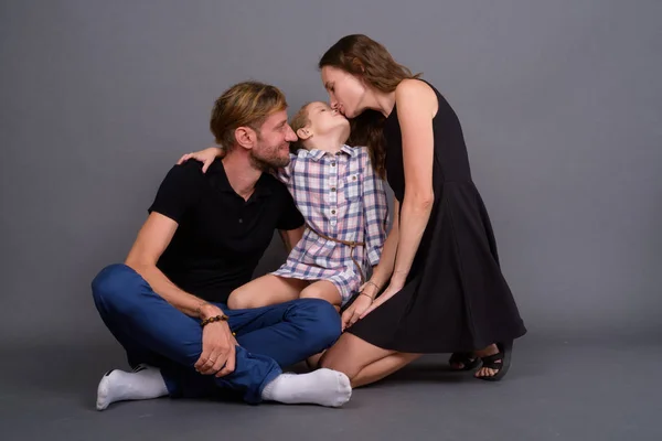 Junge glückliche Familie, die vor grauem Hintergrund zusammenhält — Stockfoto