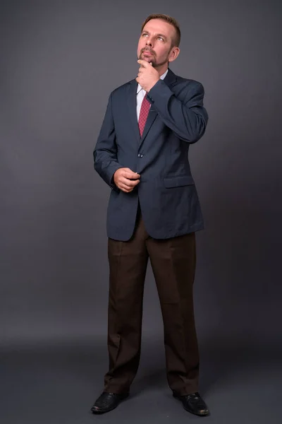 Blond bebaarde zakenman met sikje tegen grijze achtergrond — Stockfoto
