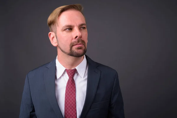 Hombre de negocios barbudo rubio con perilla sobre fondo gris —  Fotos de Stock