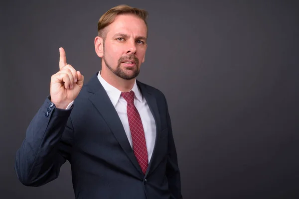 Hombre de negocios barbudo rubio con perilla sobre fondo gris —  Fotos de Stock