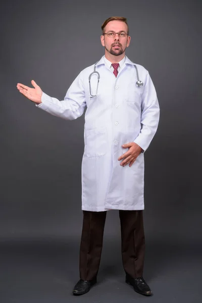 Biondo barbuto uomo medico con pizzetto contro sfondo grigio — Foto Stock