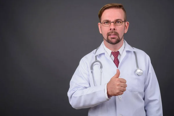 Hombre rubio barbudo médico con perilla sobre fondo gris — Foto de Stock