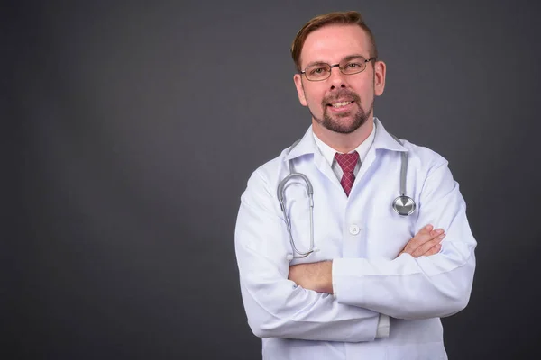 Hombre rubio barbudo médico con perilla sobre fondo gris — Foto de Stock