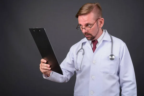 Hombre rubio barbudo médico con perilla sobre fondo gris — Foto de Stock