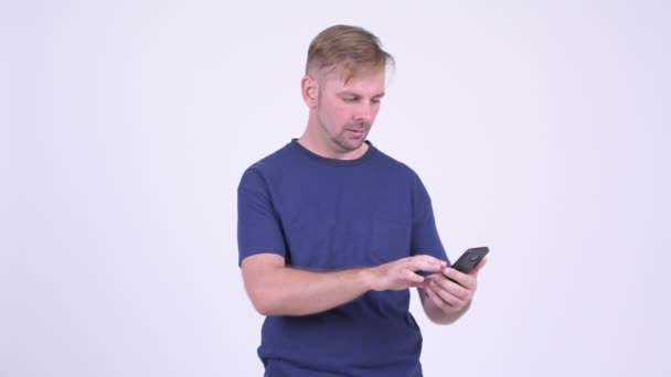 Retrato del hombre rubio usando el teléfono y mirando sorprendido — Vídeos de Stock