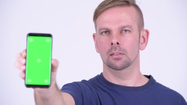 Portret van gelukkig blonde man die lacht terwijl het tonen van de telefoon — Stockvideo