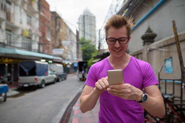 Ο άνθρωπος ευτυχισμένος τουριστικά χαμογελώντας και χρήση κινητού τηλεφώνου στο δρόμο σε εξωτερικούς χώρους — Φωτογραφία Αρχείου
