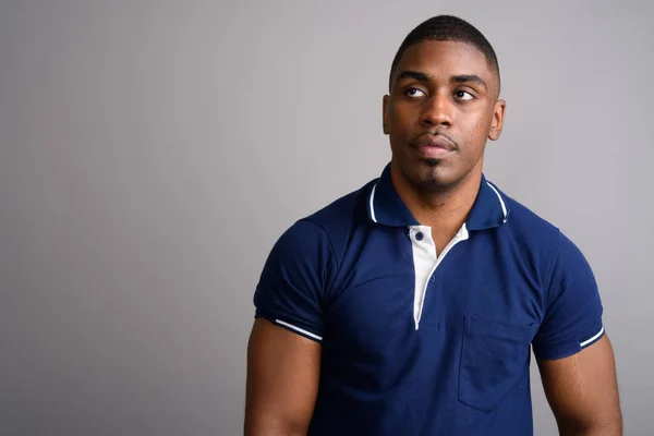 Young handsome African man wearing blue polo shirt against gray — Stock Photo, Image