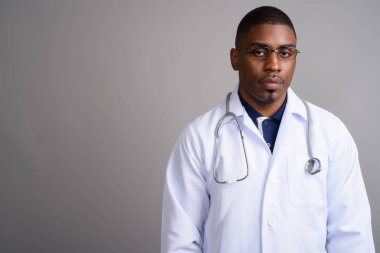Gri arka planda genç yakışıklı Afrikalı doktor