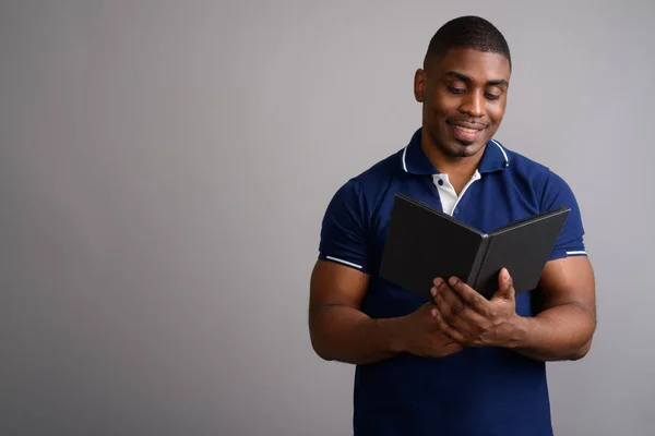 Young handsome African man wearing blue polo shirt against gray — Stock Photo, Image