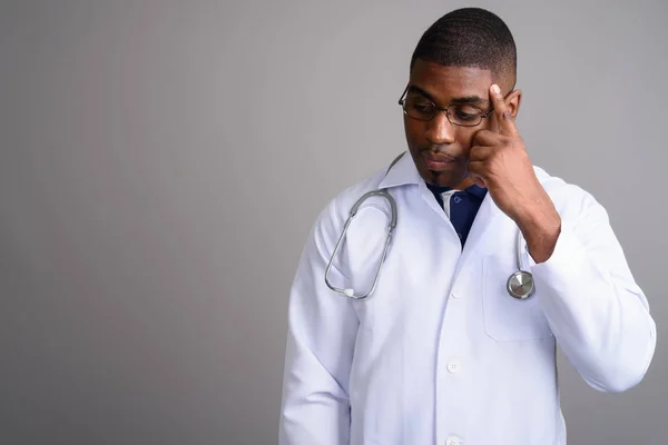 Joven guapo africano hombre médico contra gris fondo —  Fotos de Stock