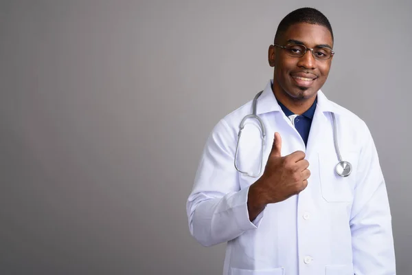 Young handsome African man doctor against gray background — Stock Photo, Image