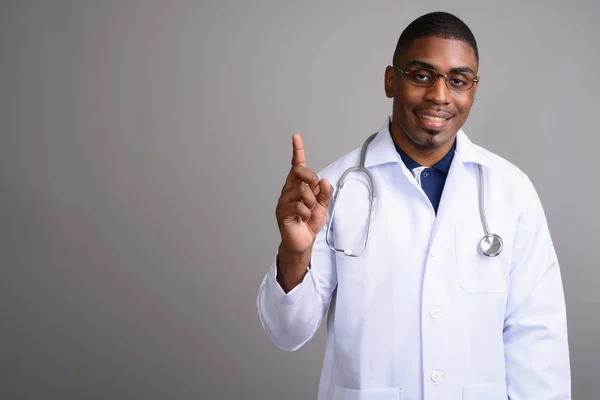 Young handsome African man doctor against gray background — Stock Photo, Image