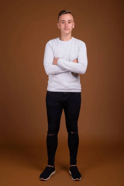 Young handsome man with blond hair against brown background — Stock Photo, Image