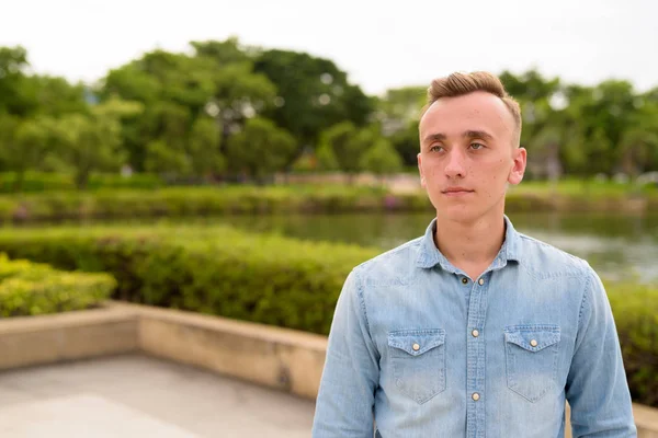 Joven hombre guapo con el pelo rubio relajándose en el parque — Foto de Stock