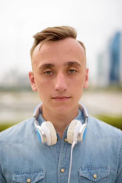 Face of man in park holding headphones — Stock Photo, Image