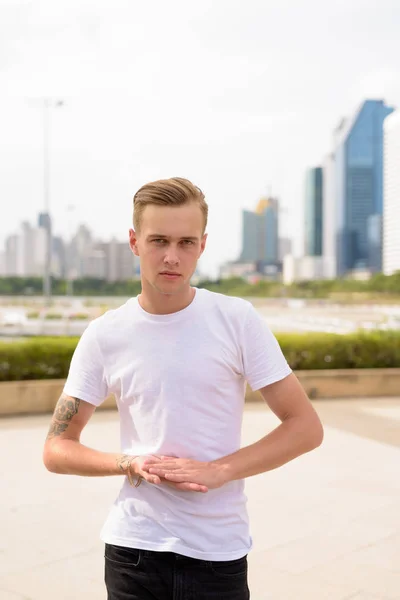 Jeune homme beau aux cheveux blonds relaxant au parc — Photo