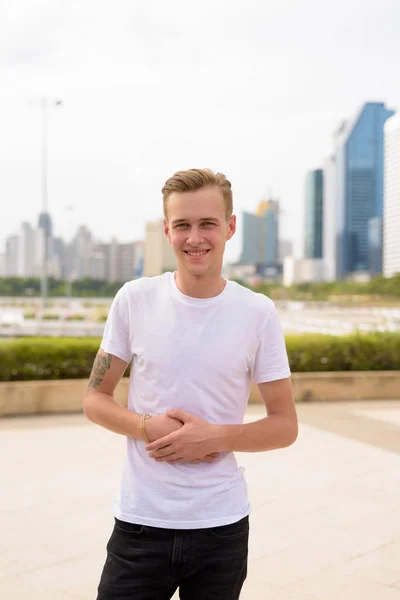 Jeune homme beau aux cheveux blonds relaxant au parc — Photo