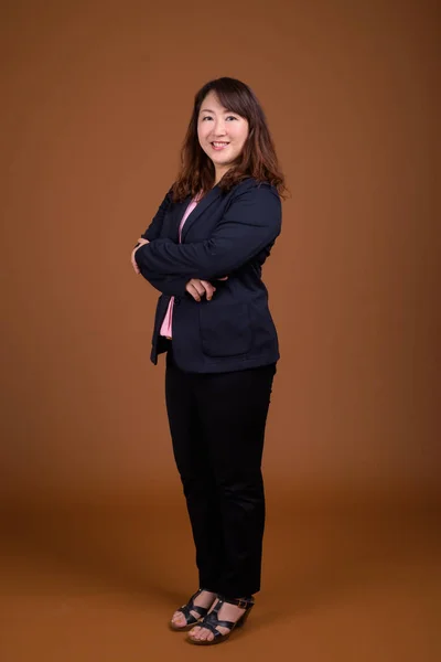 茶色の背景に対して成熟した美しいアジア女性実業家 — ストック写真