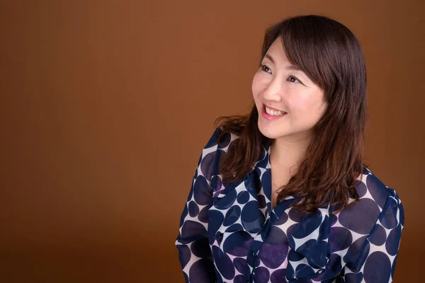 Madura hermosa mujer de negocios asiática contra fondo marrón —  Fotos de Stock