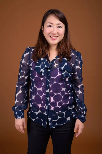 茶色の背景に対して成熟した美しいアジア女性実業家 — ストック写真