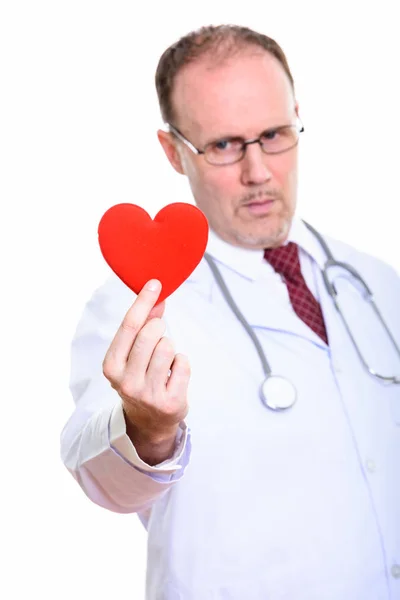 Студійний знімок зрілого лікаря, що тримає червоне серце з фокусом на — стокове фото