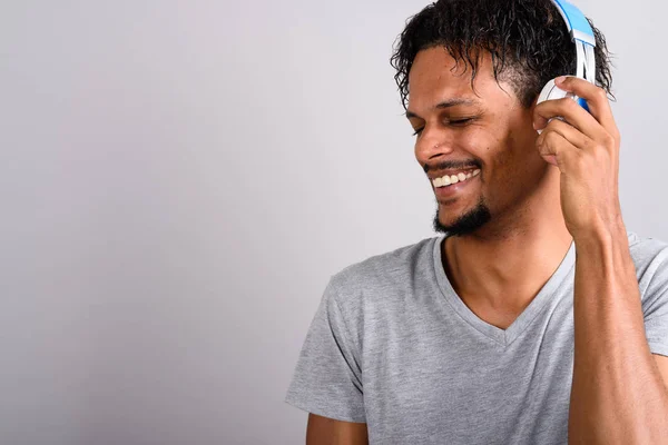 Jovem barbudo bonito homem africano ouvindo música contra gr — Fotografia de Stock