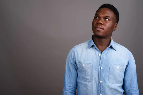 Joven hombre africano con camisa de mezclilla sobre fondo gris —  Fotos de Stock