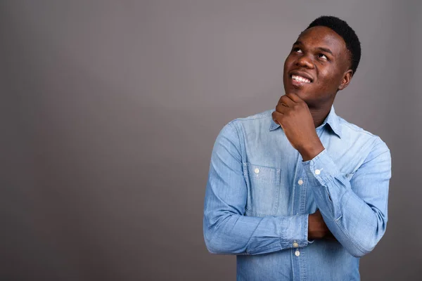 Joven hombre africano con camisa de mezclilla sobre fondo gris —  Fotos de Stock